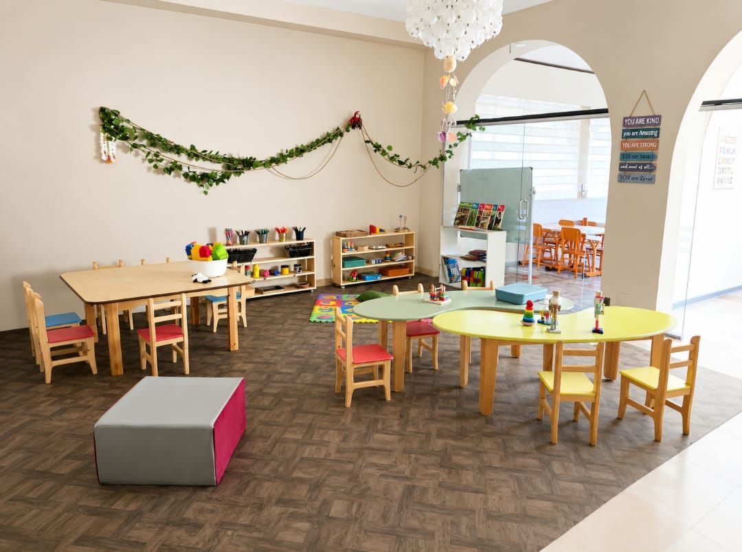 La grande salle lumineuse avec ses tables colorées et ses étagères de jeux